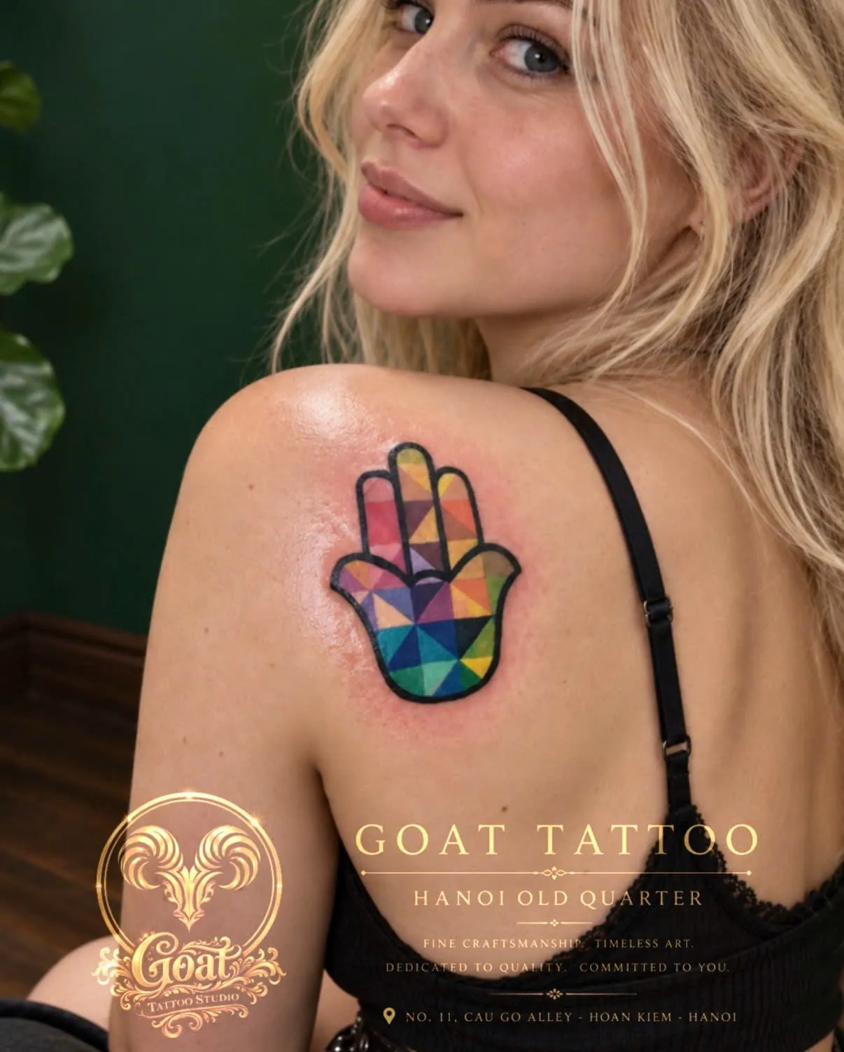 A hamsa hand filled with colorful geometric triangles, tattooed on the shoulder, by GOAT Tattoo Studio Hanoi.