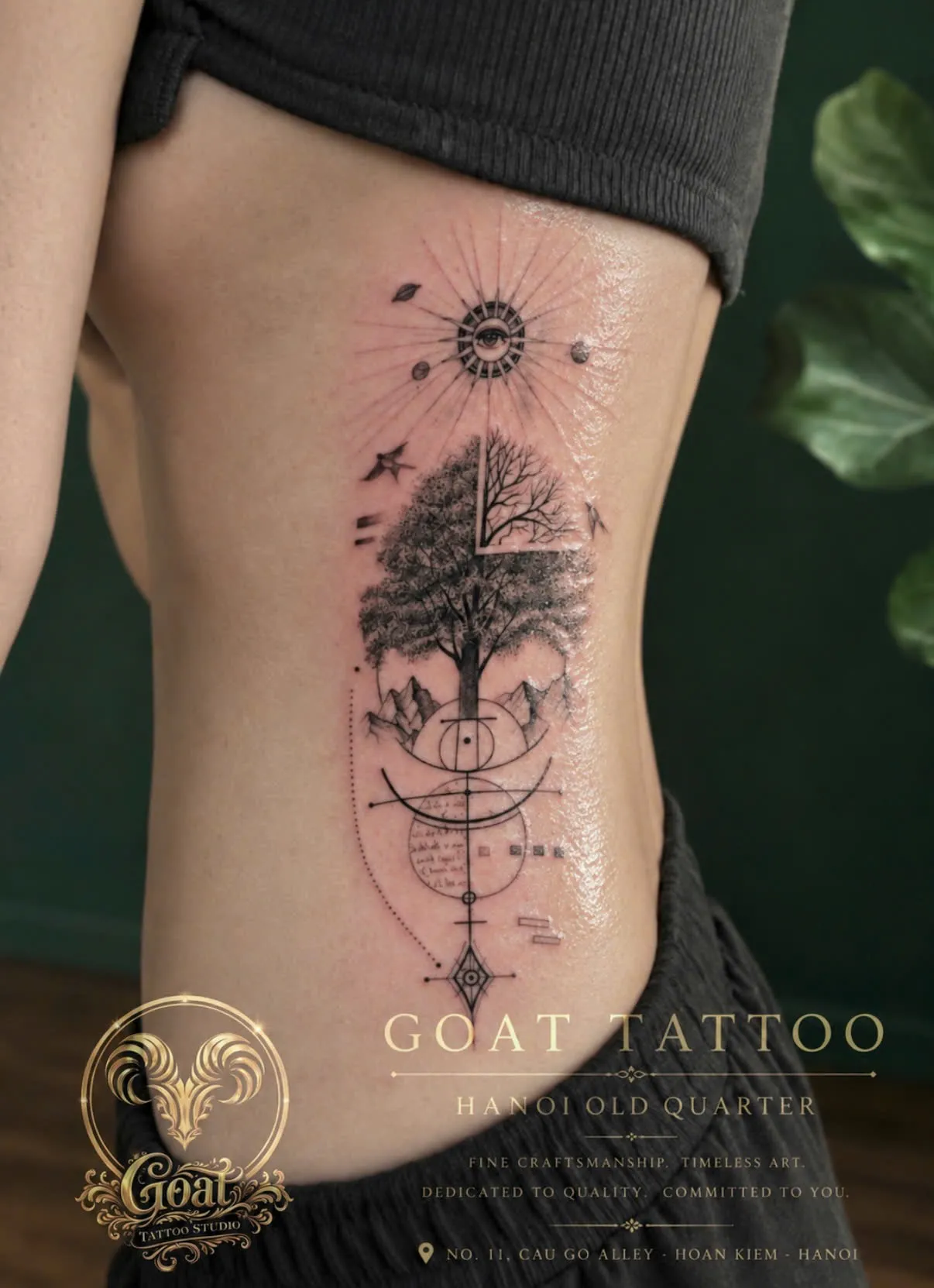 A fine line tattoo combining a tree, mountains, and sacred geometry symbols down the ribs, by GOAT Tattoo Studio Hanoi.