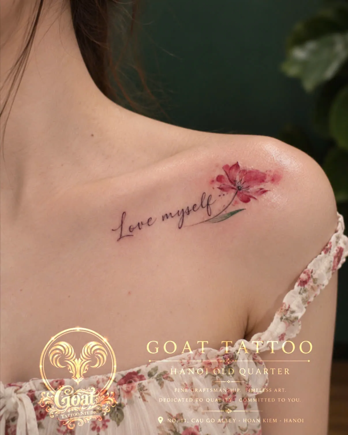 A watercolor-style pink flower paired with a Love Myself script, tattooed across the collarbone, by GOAT Tattoo Studio Hanoi.