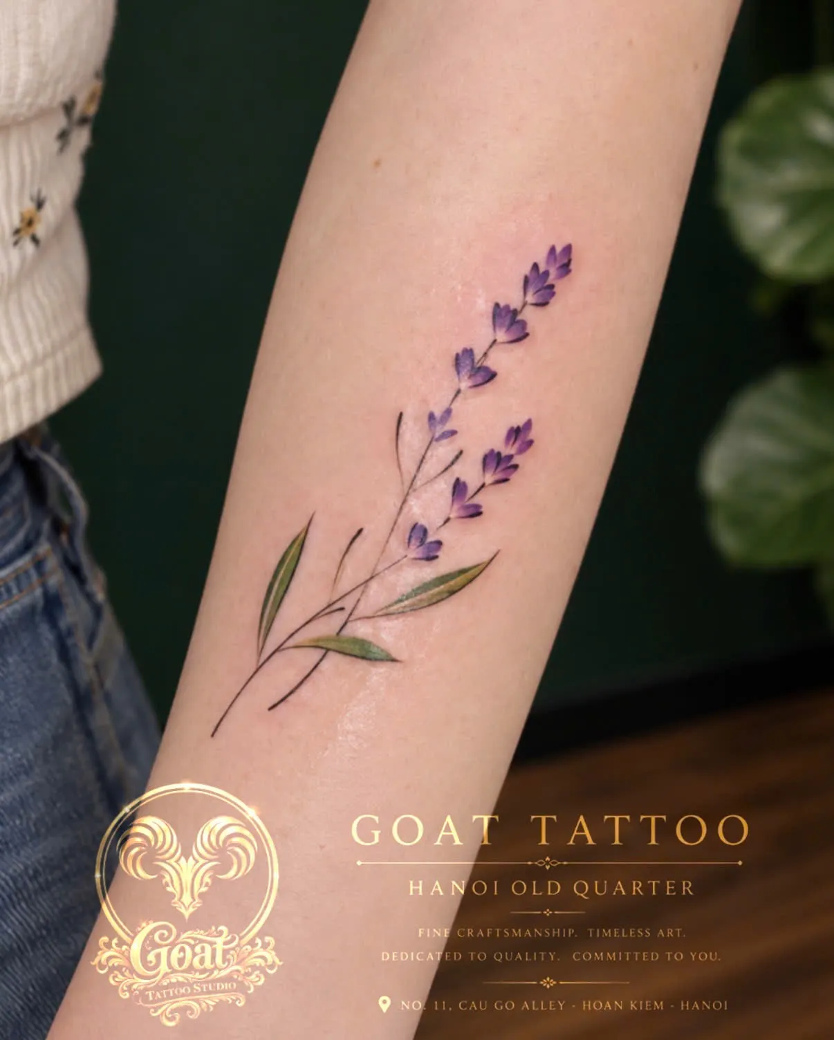 A purple watercolor-style lavender sprig tattoo on the forearm, by GOAT Tattoo Studio in Hanoi's Old Quarter.
